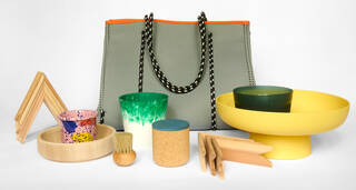 A green bag surrounded by colourful practical building materials including some wooden frames,  yellow bowl and a brown brush