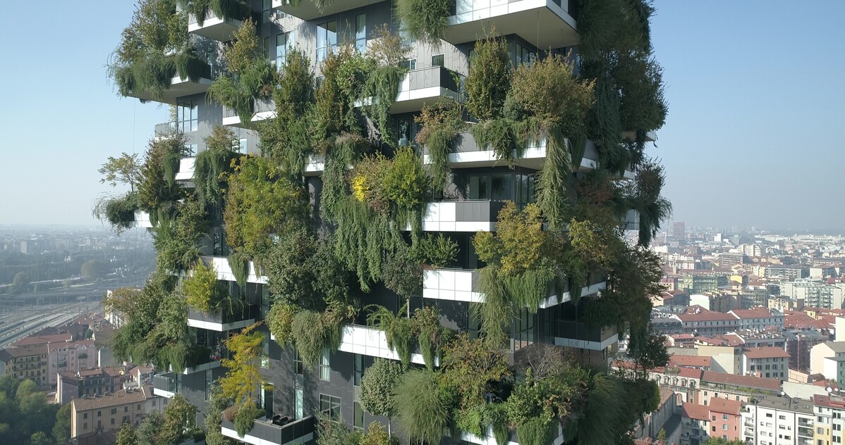 A skyscraper building with wraparound cube shaped balconies, each overflowing with greenery