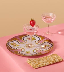 Crystal coupe glasses and a plate inspired by Sevres porcelain adorn a pastel pink tabletop.